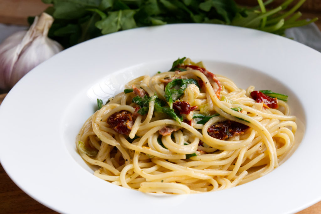 Spaghetti mit getrockneten Tomaten und Rucola in einem tiefen Teller serviert. | Lieblingsrezept | Panama Quadrat
